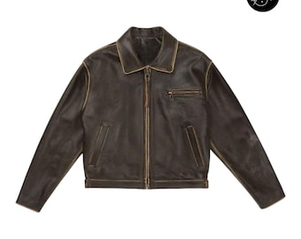 May include: A brown leather jacket with a zip-up front, a small chest pocket, and two side pockets. The jacket has a classic collar and a distressed, vintage look. The jacket is a cropped style.