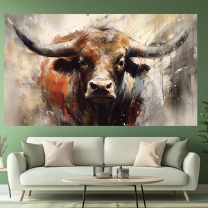 May include: A large canvas print of a bull's head, rendered in an abstract style. The artwork features a close-up of the bull's face with prominent horns, showcasing a palette of browns, oranges, and whites. The painting is displayed above a white sofa.