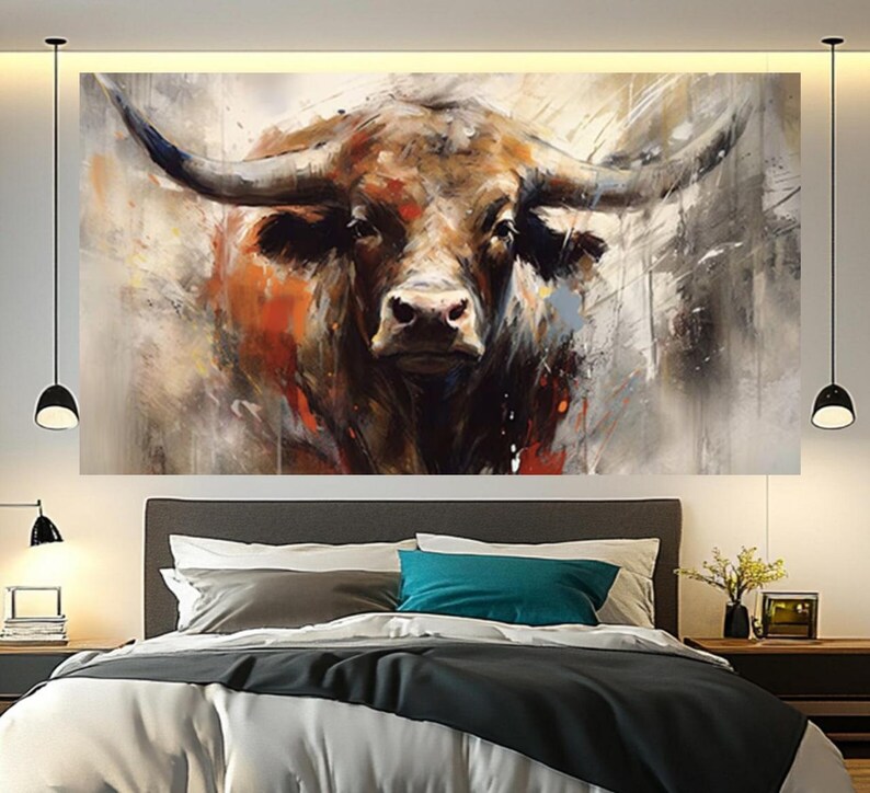May include: A large canvas art print of a bull's head, painted in a modern, abstract style. The artwork features a close-up of the bull's face with prominent horns, rendered in shades of brown, orange, and gray. The painting is displayed above a bed.