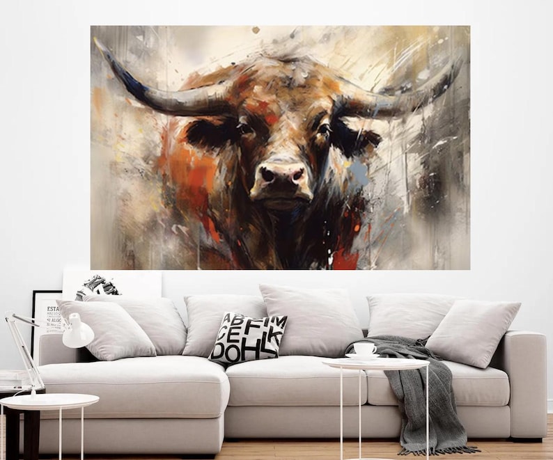 May include: A large canvas print of a bull's head, rendered in an abstract style. The artwork features a palette of browns, oranges, and grays, with the bull's horns prominently displayed. The painting is mounted on a white wall above a light-colored sofa.