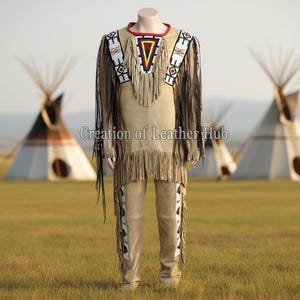 May include: A tan-coloured Native American outfit, including a shirt and trousers, displayed on a mannequin. The shirt features fringe, beadwork, and a geometric design. The trousers have decorative panels. The text "Creation of Leather Hub" is visible.