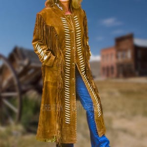 May include: A long brown suede coat with fringe and bead detailing. The coat has a long, flowing silhouette and is perfect for a western or bohemian look.