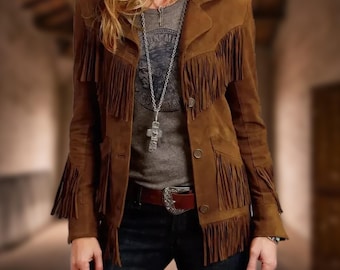 May include: A brown suede jacket with fringe detailing. The jacket has a button closure and two pockets. The model is wearing a grey t-shirt with a silver necklace and a brown belt.