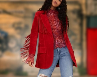 May include: A red suede jacket with fringe detailing on the sleeves and collar. The jacket has a single button closure and is worn over a floral patterned top and blue jeans.