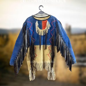 May include: A blue and beige leather jacket with fringe detailing and red stitching. The jacket has a high neckline and long sleeves. The jacket is decorated with a fringe trim around the neckline and sleeves.