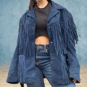 Peut inclure: Une veste en jean bleu avec des d&eacute;tails en franges. La veste a une fermeture boutonn&eacute;e &agrave; l'avant et deux poches &agrave; rabat.