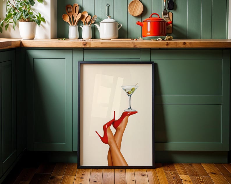 Print resting on the floor of a green kitchen with a wooden floor and red teapot nearby. The vibrant red shoes and martini contrast with earthy surroundings.