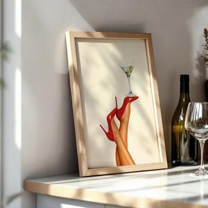 Framed red heels martini print on a white circular table. Paired with white florals and wine glasses, it’s styled for a chic brunch or celebration vibe.