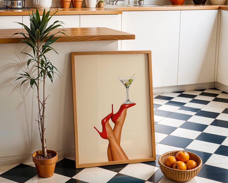 Martini print with red heels placed on the floor of a white kitchen with checker tile. Surrounded by greenery and oranges, creating a chic, fresh look.
