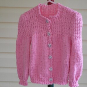 Hand knit girl&#39;s pink cardigan sweater with flower buttons