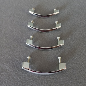 May include: Four chrome cabinet pulls in different sizes. The pulls are all in the shape of a rounded rectangle with rounded edges.