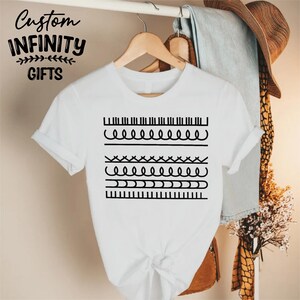 May include: White t-shirt with a black graphic design featuring various line patterns. The shirt is hanging on a wooden hanger. The text "Custom Infinity Gifts" is printed at the top left of the shirt.