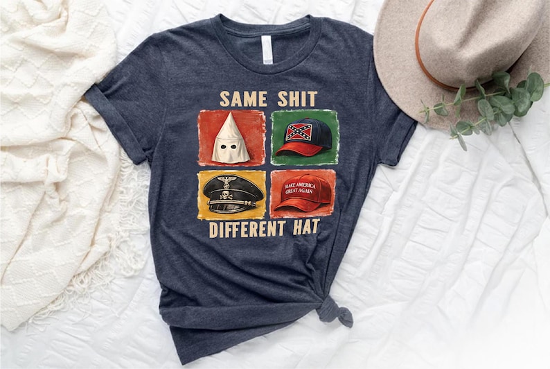 May include: Dark blue t-shirt with the text "SAME SHIT DIFFERENT HAT" and four images of hats. The hats include a KKK hood, a Confederate flag hat, a Nazi hat, and a "Make America Great Again" hat.