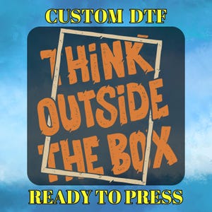 May include: A square design with the text "THINK OUTSIDE THE BOX" in orange, inside a white frame, on a dark blue background. The words "CUSTOM DTF" and "READY TO PRESS" are in yellow above and below the main text.
