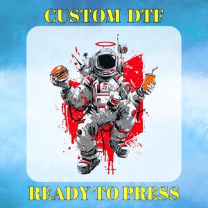 May include: DTF graphic featuring an astronaut in a spacesuit holding a burger and a drink. The astronaut is surrounded by red paint splatters. Text at the top reads "CUSTOM DTF" and at the bottom "READY TO PRESS".