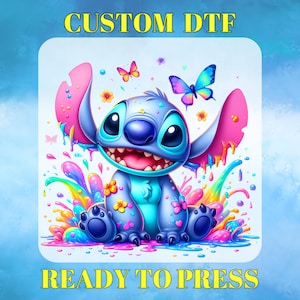 May include: A colorful graphic featuring a cartoon character with large ears, blue fur, and a wide grin. The image includes butterflies, flowers, and a splash of rainbow colors. Text at the top reads "CUSTOM DTF" and at the bottom "READY TO PRESS."