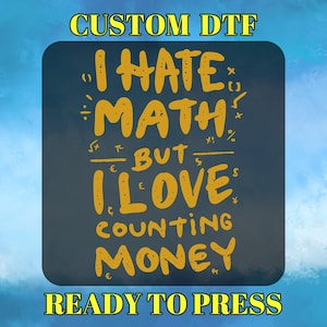 May include: A navy blue graphic with the text "I HATE MATH BUT I LOVE COUNTING MONEY" in yellow. The words are surrounded by math symbols and currency symbols. The words "CUSTOM DTF" and "READY TO PRESS" are at the top and bottom.