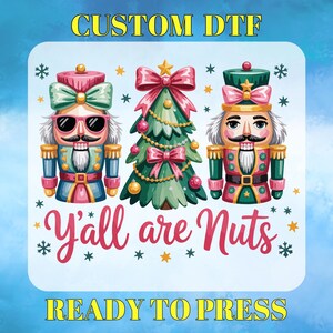 May include: A square DTF transfer design featuring two nutcrackers, a Christmas tree, snowflakes, and the text "Y'all are Nuts." The design includes the text "CUSTOM DTF" and "READY TO PRESS" in yellow.