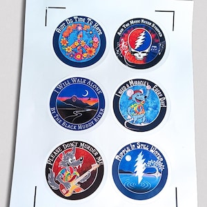 May include: A sheet of six circular stickers with colorful designs and text. The stickers feature illustrations of a peace sign, a skull, a landscape, a mouse, a wolf playing guitar, and a lightning bolt over water. Text includes phrases like "Ain't Do Time To Hate" and "Ripple In Still Water."