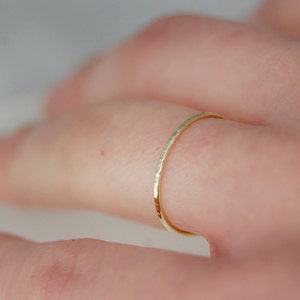 May include: A thin gold band ring with a hammered texture.