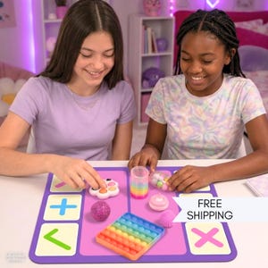 May include: A purple rectangular play mat featuring white squares with pink and blue symbols, accompanied by a rainbow-colored square bubble popper, a clear cylinder, a purple glitter sphere, a small pink container, and a white flower-shaped popper.
