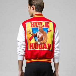 Könnte beinhalten: Rote und weiße Collegejacke mit einem großen Hulk Hogan-Motiv auf dem Rücken. Die Jacke hat einen roten Körper, weiße Ärmel und gelb-rot gestreifte Verzierungen. Das Motiv enthält den Text "Hulk Hogan".