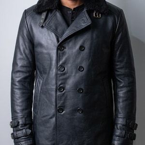 May include: A black leather double-breasted coat with a black faux fur collar. The coat features multiple buttons, buckle details on the sleeves, and a classic pea coat design. The coat is a dark charcoal color.