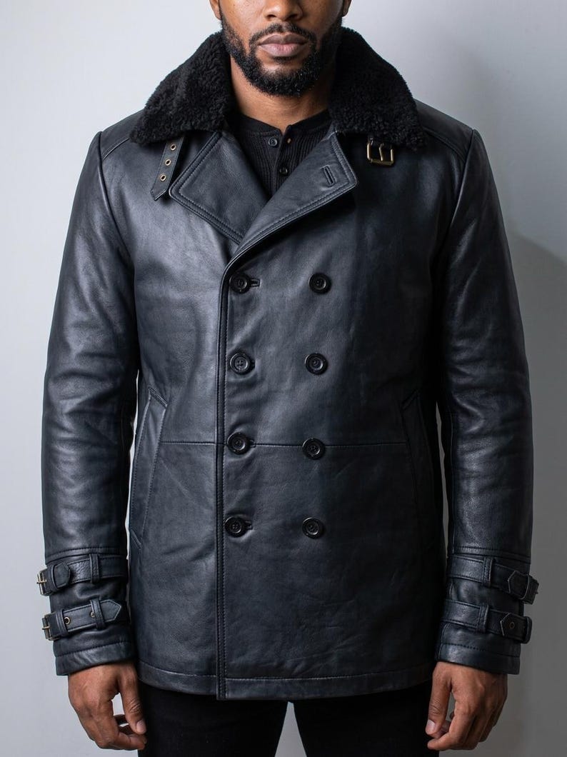May include: A black leather double-breasted coat with a black faux fur collar. The coat features multiple buttons, buckle details on the sleeves, and a classic pea coat design. The coat is a dark charcoal color.