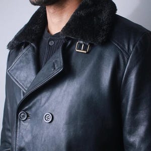 May include: Black leather double-breasted coat with a black faux fur collar. The coat features a gold-colored buckle and four black buttons. The coat is a classic design, suitable for cold weather.