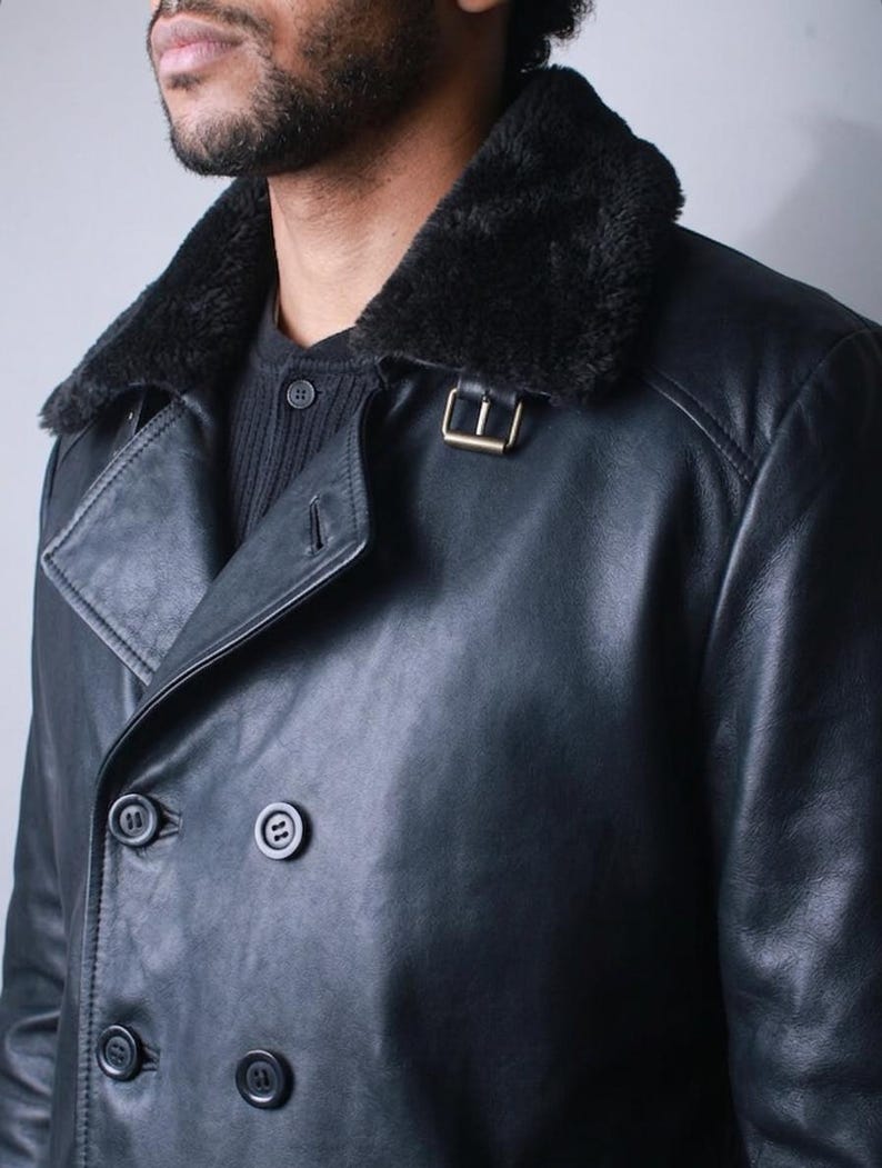May include: Black leather double-breasted coat with a black faux fur collar. The coat features a gold-colored buckle and four black buttons. The coat is a classic design, suitable for cold weather.