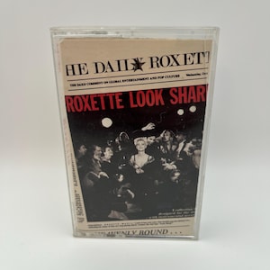 May include: A vintage cassette tape with the text "HE DAILY ROXET" and "ROXETTE LOOK SHARP" in red and black. The cassette case is clear, and the cover features a black and white image of a crowd and a woman.