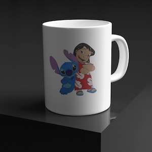 May include: White ceramic mug featuring a blue alien character and a girl with black hair wearing a red dress with white flowers. The alien character has large blue eyes and a big smile. The girl has a big smile and is holding her arms crossed.