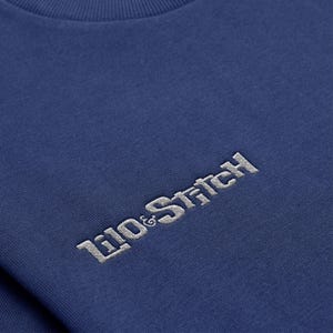 May include: A navy blue t-shirt with a white embroidered logo that reads "Lilo & Stitch".
