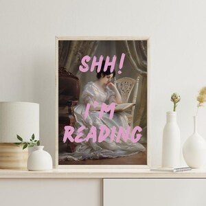 May include: A framed print of a woman in a white dress reading a book. The text "SHHH! I'M READING" is written in pink letters on the print.