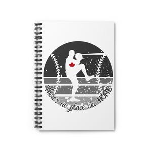 May include: A white spiral notebook with a black and white illustration of a baseball player with a Canadian flag on their chest. The illustration is in a circle with the text "There's no place like HOME" around it.