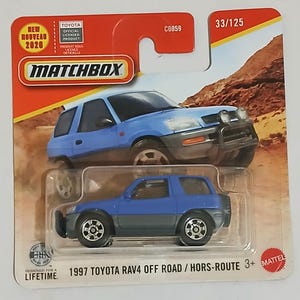 May include: A Matchbox toy car of a 1997 Toyota RAV4 Off Road. The die-cast model is blue and grey, with black wheels and a front bumper. The packaging includes the Matchbox logo, Toyota branding, and the text "NEW NOUVEAU 2020".