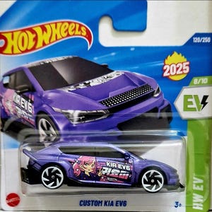 May include: A purple Hot Wheels Custom Kia EV6 die-cast car. The car has an anime graphic and the text "KIA EV6". The packaging includes the Hot Wheels logo, the year 2025, and the EV symbol.