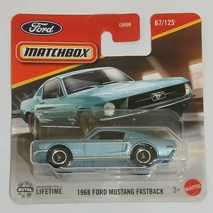 May include: A Matchbox die-cast model of a 1968 Ford Mustang Fastback in light blue. The packaging includes the Ford and Matchbox logos, and the text "Designed for a Lifetime."