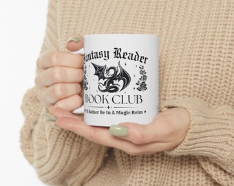 May include: White ceramic mug featuring the text "Fantasy Reader Book Club" in a gothic font, with a black dragon illustration. The mug also includes the phrase "I'd Rather Be In A Magic Realm".