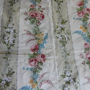 Puede incluir: Tela blanca con un patr&oacute;n repetido de rosas rosas y blancas, flores azules y amarillas y hojas verdes sobre un fondo rayado verde claro.