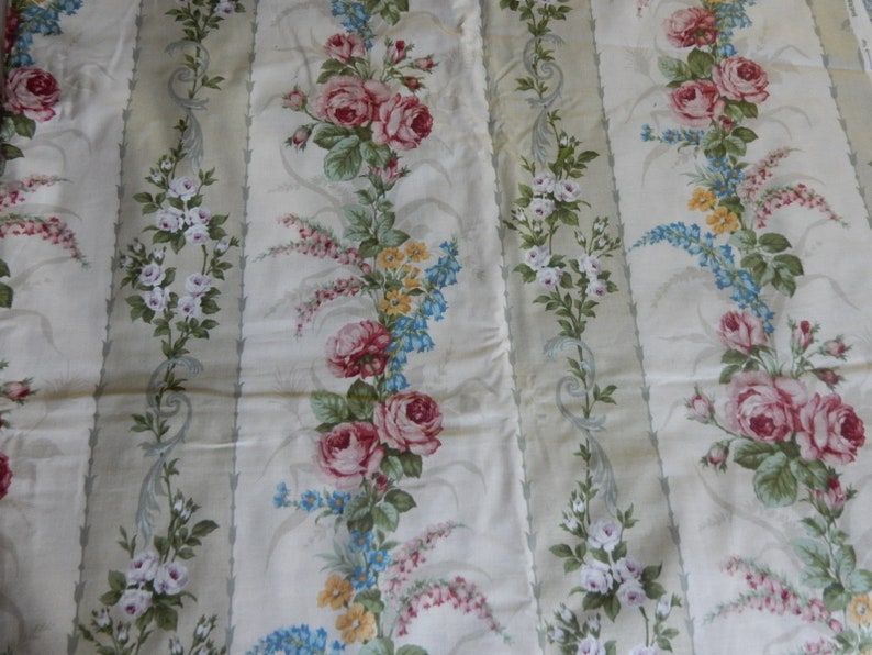 Puede incluir: Tela blanca con un patr&oacute;n repetido de rosas rosas y blancas, flores azules y amarillas y hojas verdes sobre un fondo rayado verde claro.