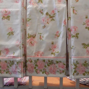 May include: Three white fabric panels with a pink rose pattern. The panels have a pink and white trim along the bottom.