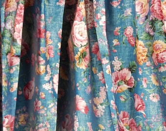 May include: A blue floral valance with pink, yellow, and white flowers. The valance is made of a soft, textured fabric and has a ruffled edge.