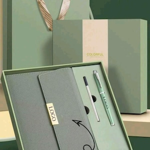 May include: A green gift set featuring a notebook, pen, and refill, presented in a matching box and gift bag. The notebook has a gold-coloured logo. The box is labelled "COLORFUL". The text "Customize here" is also visible.