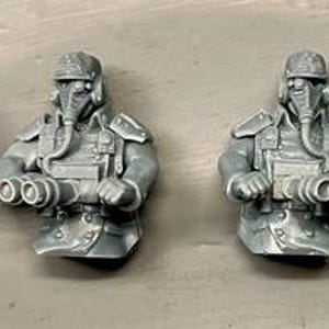 May include: Four gray miniature figures of a person in a military-style uniform, helmet, and face mask. Two figures hold binoculars, while the other two point with their arms. The figures are detailed with belts and pockets.
