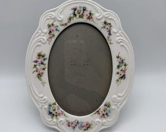 Marco de fotos ovalado vintage de cerámica blanca con diseño floral para una foto de 5x7 pulgadas, con parte trasera de terciopelo gris.