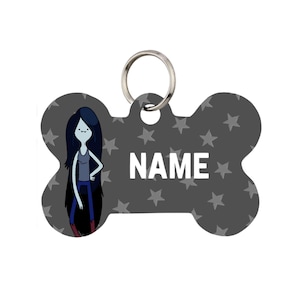 May include: Bone-shaped pet tag with a gray background and white stars. The tag features a cartoon character with long black hair, a gray top, and blue pants. The word "NAME" is printed in white.