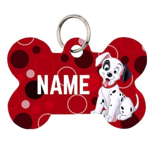 May include: A bone-shaped pet ID tag featuring a red background with dark red and pink circles. The word NAME is printed in white capital letters. A cartoon dalmatian puppy with a red collar is on the right side, and a silver metal ring is attached.