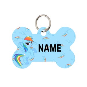 May include: A light blue, bone-shaped pet tag with a cartoon pony illustration and the word "NAME" in black. The tag features a rainbow-colored mane and tail, with clouds and rainbows scattered across the background. A silver ring is attached.