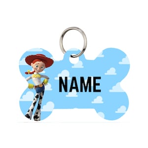 May include: A light blue, bone-shaped pet tag with the name "NAME" in black block letters. The tag features a cartoon image of Jessie from Toy Story, set against a sky-blue background with white clouds. A silver ring is attached for easy attachment to a pet's collar.